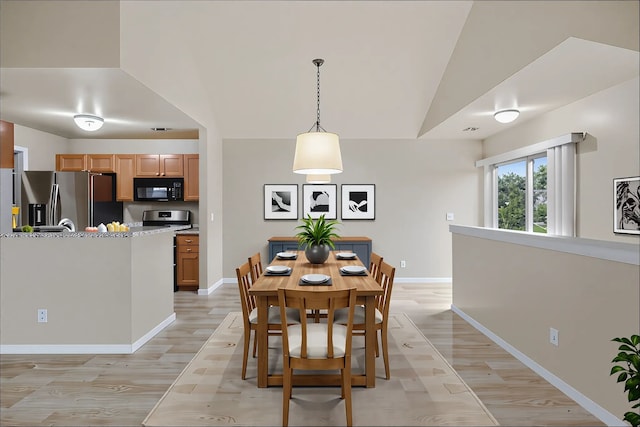 dining room with lofted ceiling, baseboards, and light wood-style floors