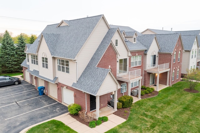 exterior space with cooling unit, brick siding, driveway, and a front yard