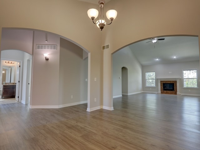 unfurnished living room featuring visible vents, ceiling fan, a high ceiling, and wood finished floors