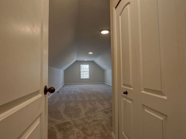 additional living space with baseboards, vaulted ceiling, and dark carpet