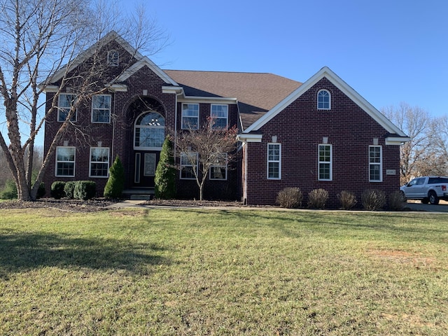 colonial inspired home featuring a front lawn and brick siding