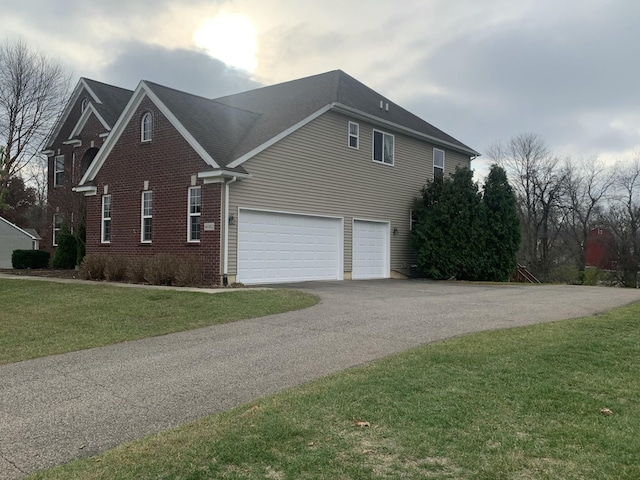view of home's exterior featuring a yard, brick siding, an attached garage, and aphalt driveway