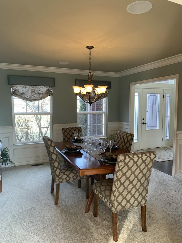 dining area featuring a wainscoted wall, visible vents, carpet flooring, and a chandelier
