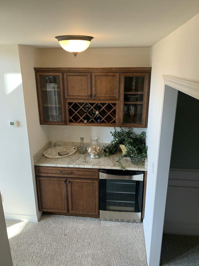 bar with beverage cooler, baseboards, light colored carpet, and bar
