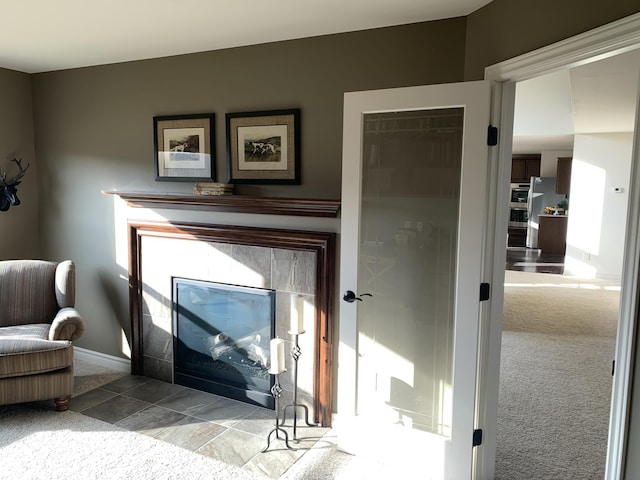 room details featuring a tiled fireplace, carpet, and baseboards