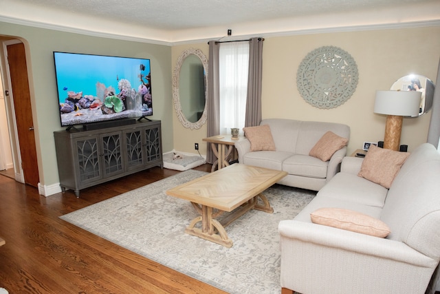 living area featuring arched walkways, baseboards, and wood finished floors