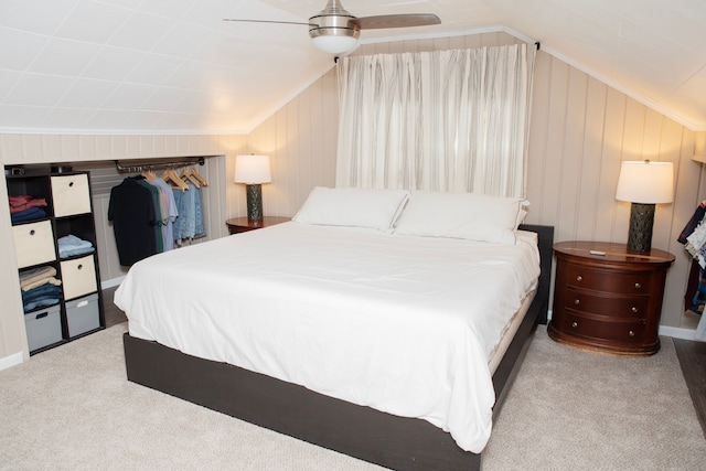 carpeted bedroom featuring lofted ceiling, wood walls, and a ceiling fan