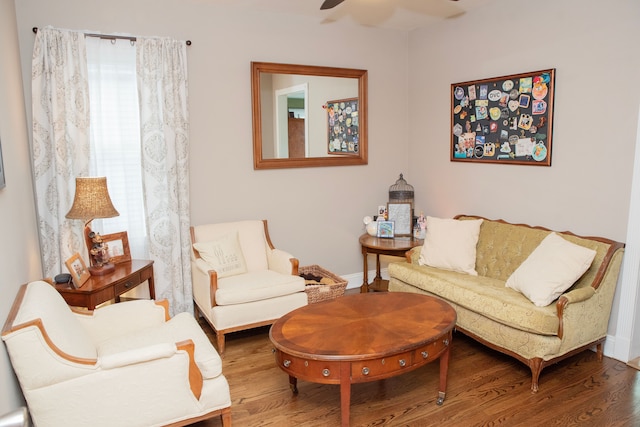 living area with a ceiling fan, baseboards, and wood finished floors