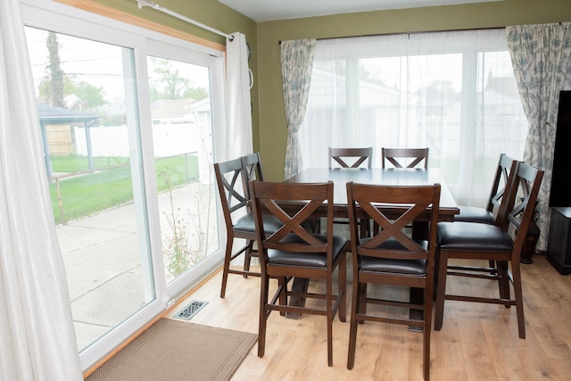 dining area with light wood-type flooring and visible vents