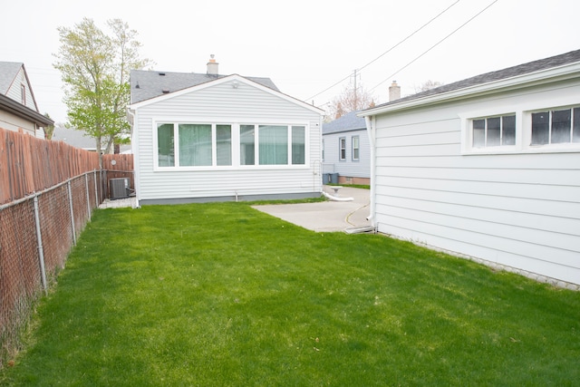 rear view of house with cooling unit, a patio area, a lawn, and a fenced backyard