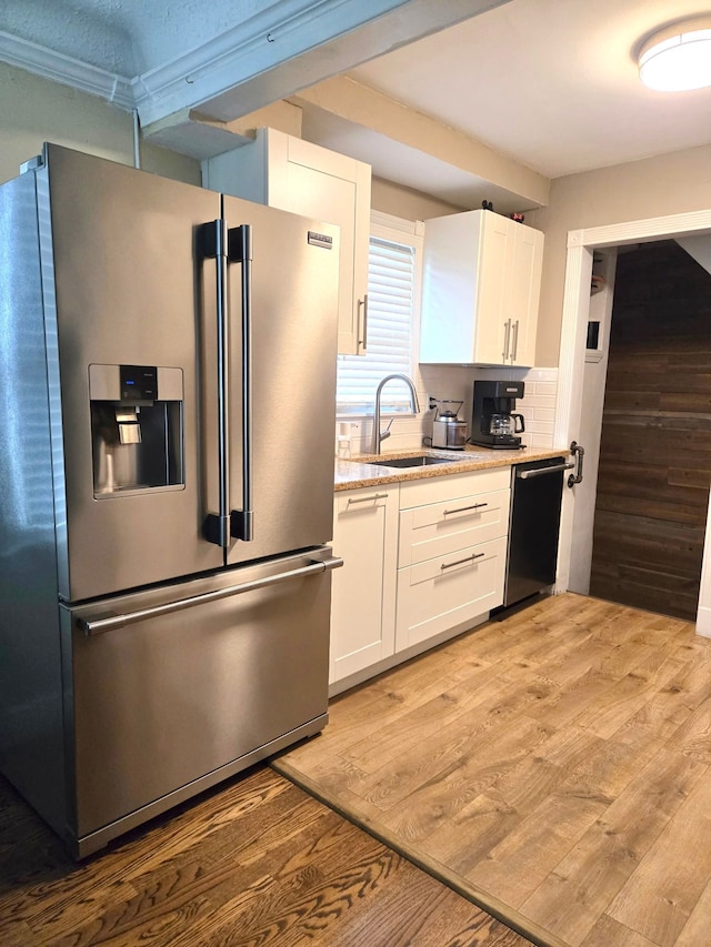 kitchen with a sink, dishwasher, light wood finished floors, stainless steel fridge, and white cabinets
