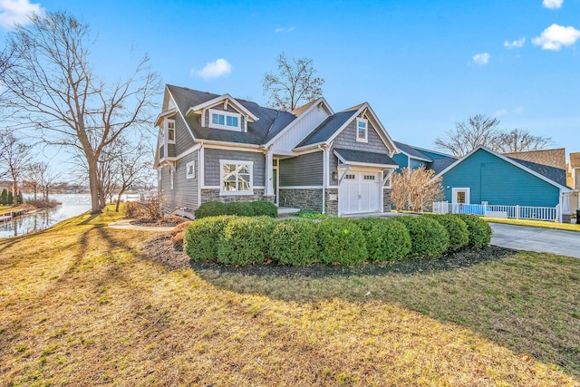craftsman house featuring a water view, an attached garage, a front yard, and stone siding