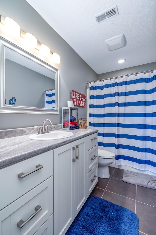 full bath with vanity, toilet, a textured ceiling, tile patterned floors, and visible vents