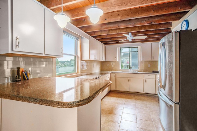 kitchen featuring beamed ceiling, freestanding refrigerator, backsplash, and a peninsula