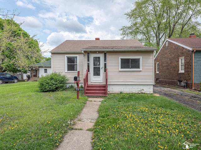 bungalow-style home with a front yard, a chimney, and entry steps