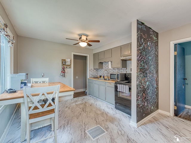 kitchen featuring black electric range oven, a ceiling fan, baseboards, backsplash, and gray cabinetry