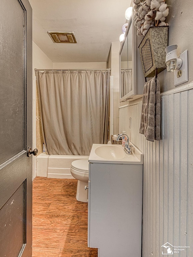 bathroom with vanity, toilet, curtained shower, wood finished floors, and visible vents