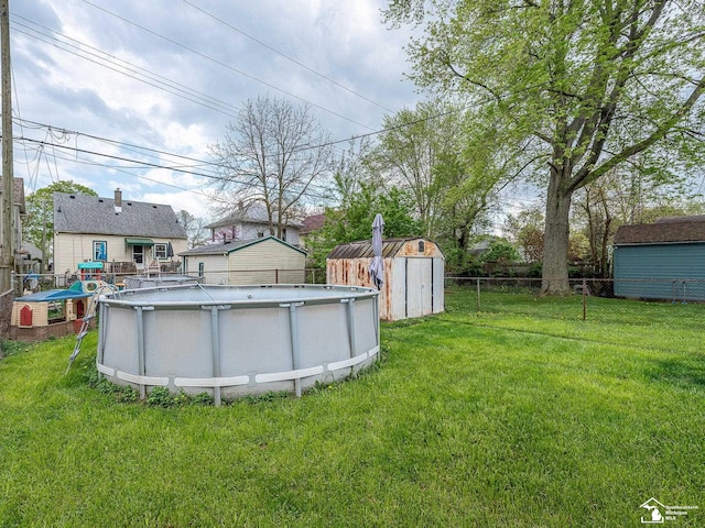 view of yard featuring fence, an outbuilding, a shed, and an outdoor pool