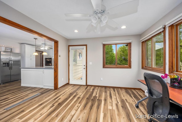 unfurnished office featuring a ceiling fan, baseboards, plenty of natural light, and wood finished floors