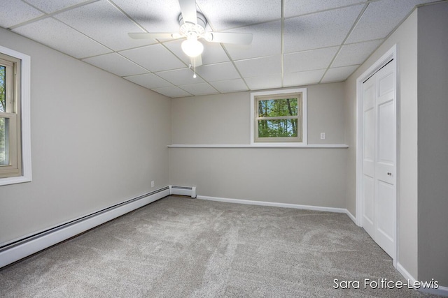 unfurnished room featuring a drop ceiling, baseboards, baseboard heating, and carpet floors