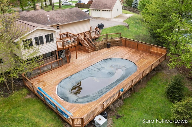 view of swimming pool featuring a wooden deck, an outdoor structure, and a lawn