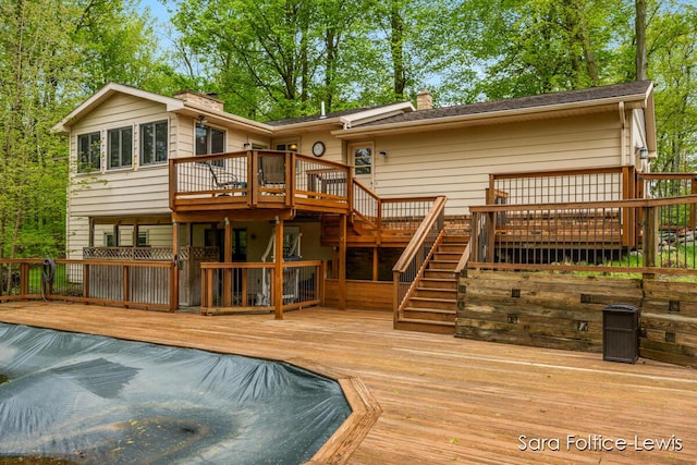 back of house with a wooden deck, stairs, and a chimney