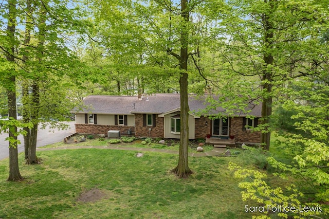 ranch-style home featuring a front lawn, roof with shingles, and aphalt driveway