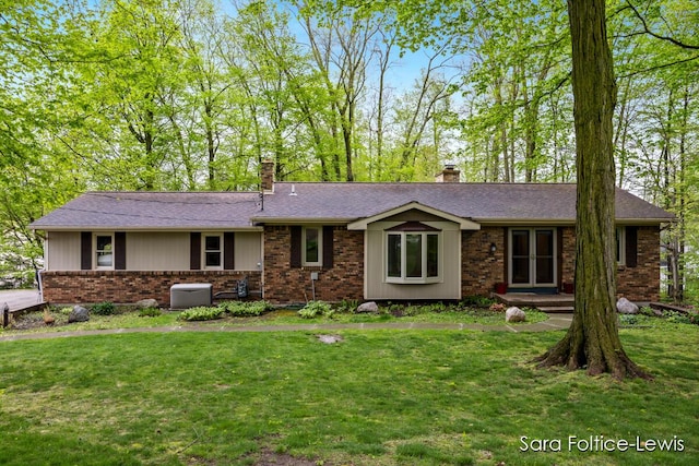 ranch-style house with brick siding, a chimney, and a front yard