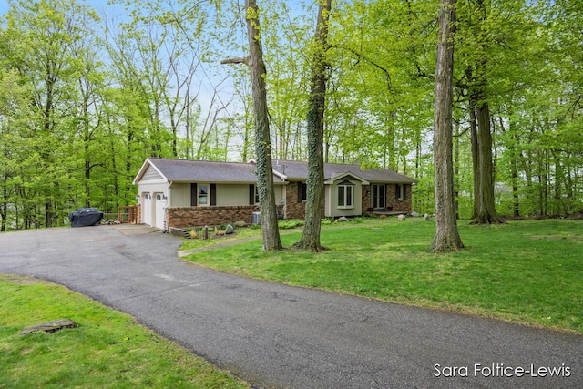single story home with a front lawn, brick siding, an attached garage, and aphalt driveway