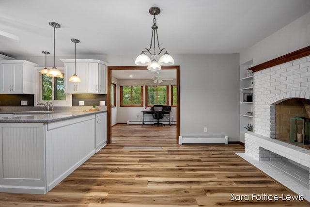 kitchen with white cabinets, a healthy amount of sunlight, light wood finished floors, and a baseboard heating unit