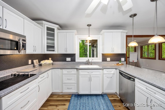 kitchen featuring stainless steel appliances, white cabinets, a sink, and wood finished floors