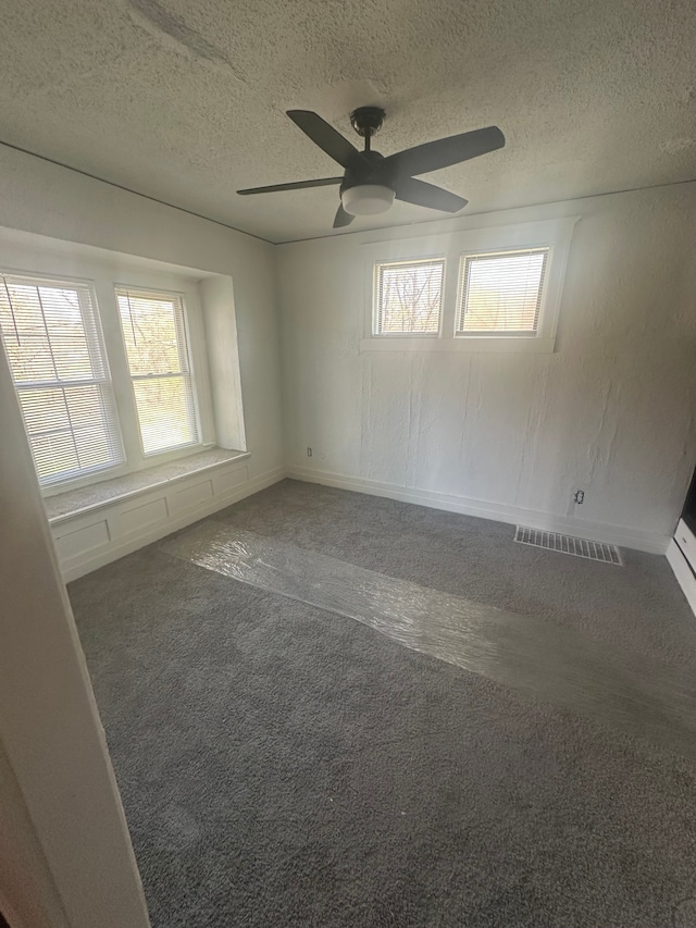 empty room featuring carpet floors, a textured ceiling, a ceiling fan, baseboards, and visible vents