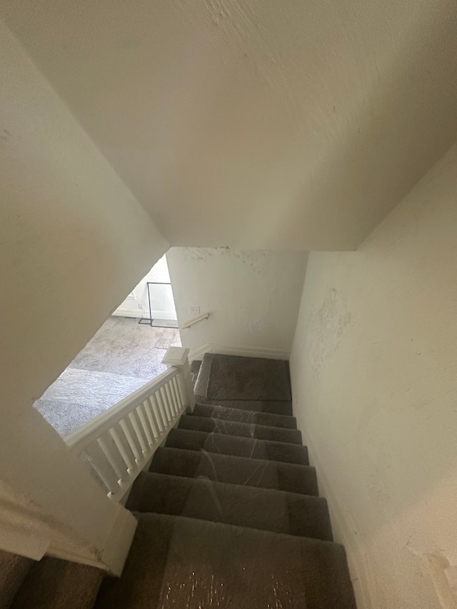 staircase with carpet floors and lofted ceiling