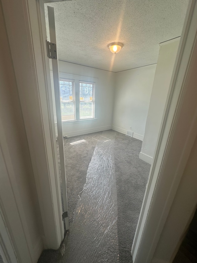unfurnished room with baseboards, carpet flooring, and a textured ceiling