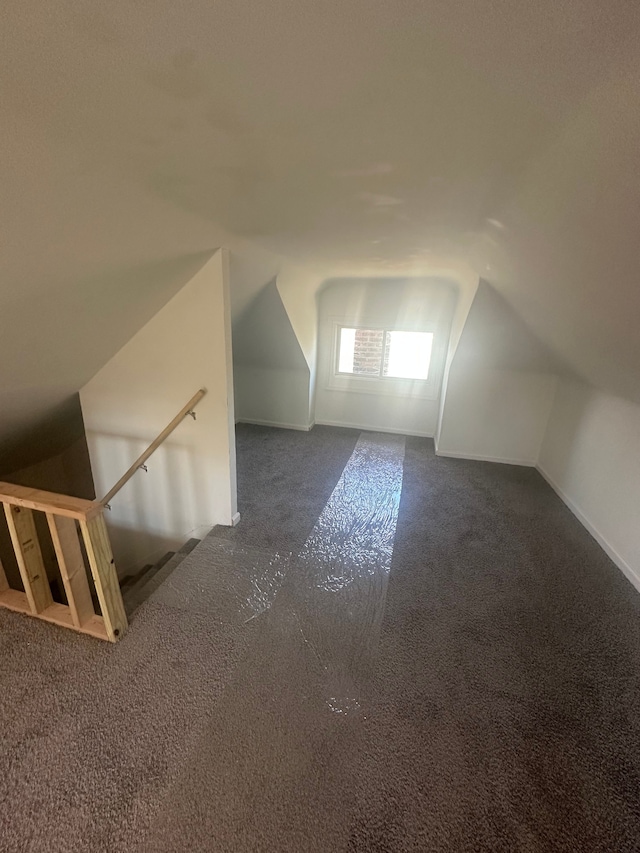 bonus room with baseboards, vaulted ceiling, and dark carpet