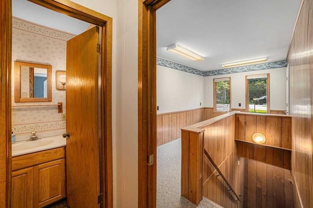 410 Orchard Ct, Saint Louis, MI 48880 - hall with a sink, a wainscoted wall, an upstairs landing, wooden walls, and wallpapered walls
