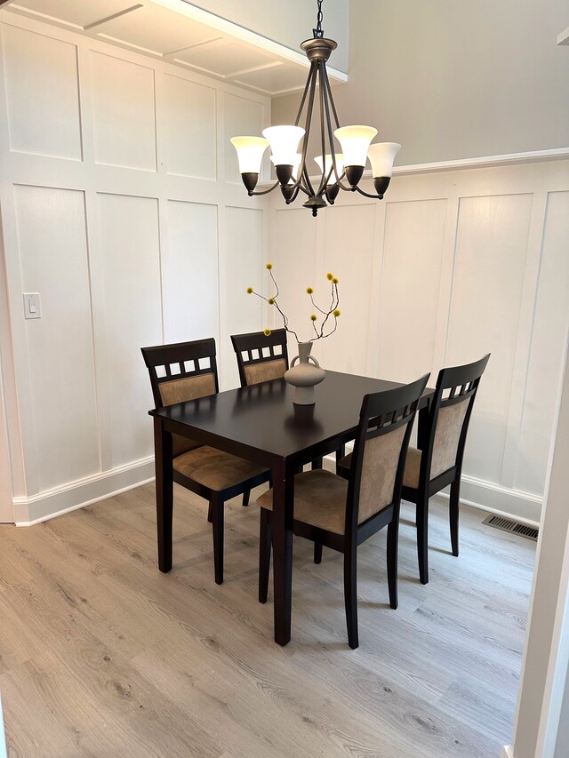 dining room with a decorative wall, a chandelier, and light wood-style floors