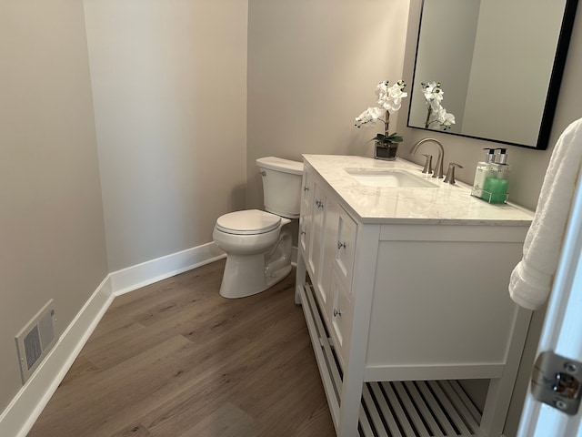 bathroom featuring baseboards, wood finished floors, toilet, vanity, and a baseboard radiator