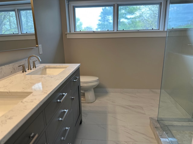 bathroom featuring marble finish flooring, plenty of natural light, toilet, and double vanity