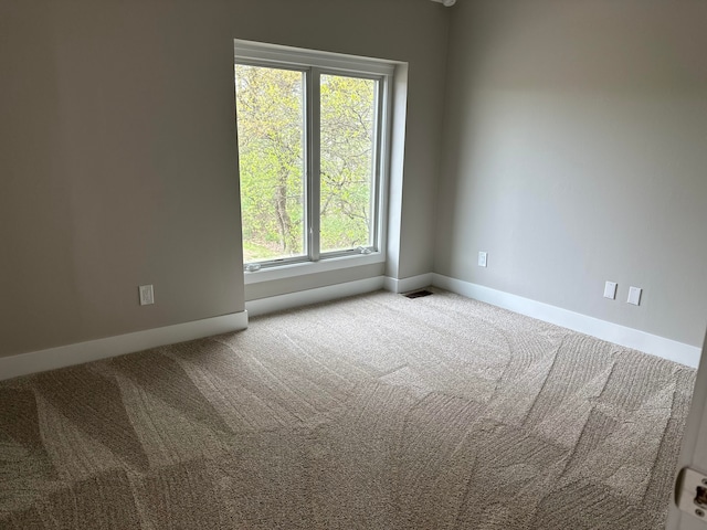 carpeted spare room featuring baseboards