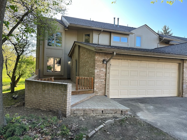 view of front of home featuring driveway, a garage, brick siding, and a shingled roof