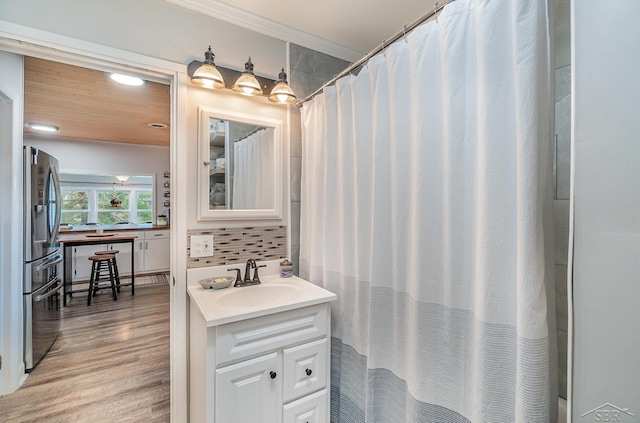 1349 Mckimmy Rd, Beaverton, MI 48612 - bathroom with tasteful backsplash, vanity, ornamental molding, and wood finished floors