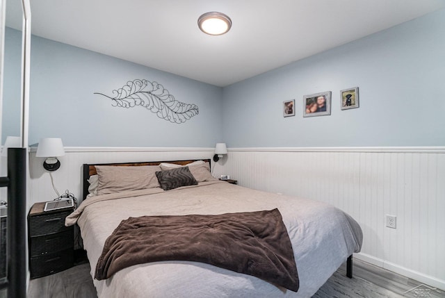 1349 Mckimmy Rd, Beaverton, MI 48612 - bedroom with a wainscoted wall, baseboards, and wood finished floors