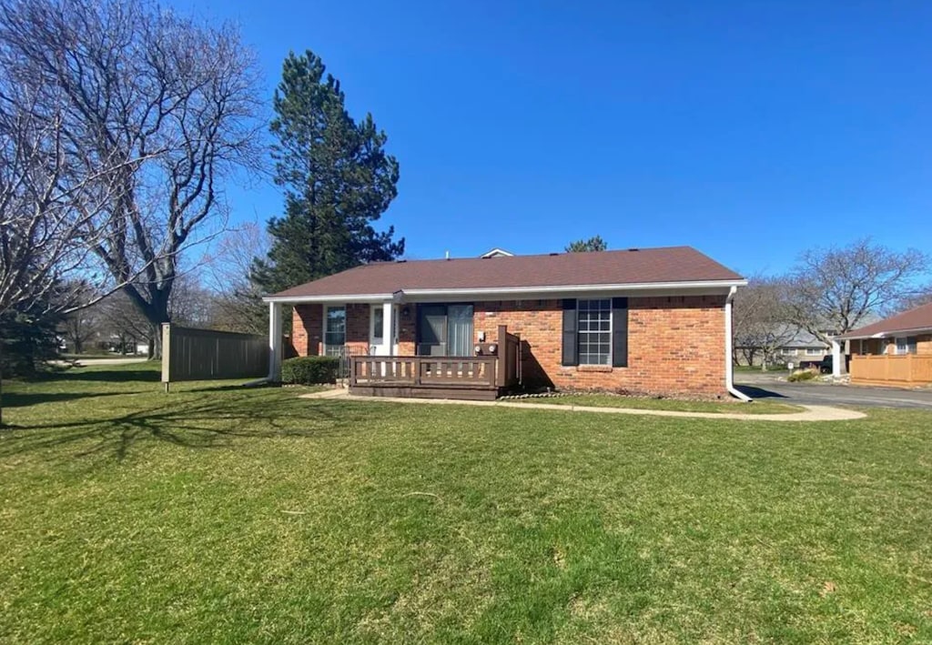 view of front of property with brick siding, a wooden deck, and a front lawn