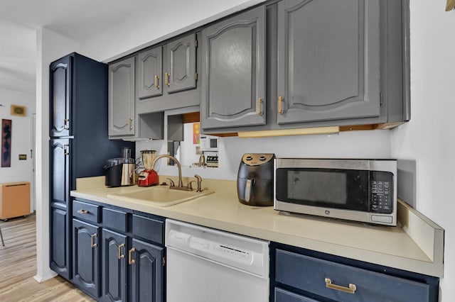 2917 Whittier Ct, Ann Arbor, MI 48104 - kitchen featuring dishwasher, a sink, stainless steel microwave, light countertops, and light wood-style flooring