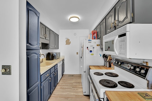 2917 Whittier Ct, Ann Arbor, MI 48104 - kitchen featuring white appliances, a sink, light countertops, light wood-style floors, and blue cabinetry