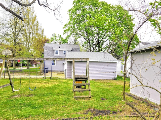 rear view of house featuring a shingled roof, fence, a yard, and a chimney