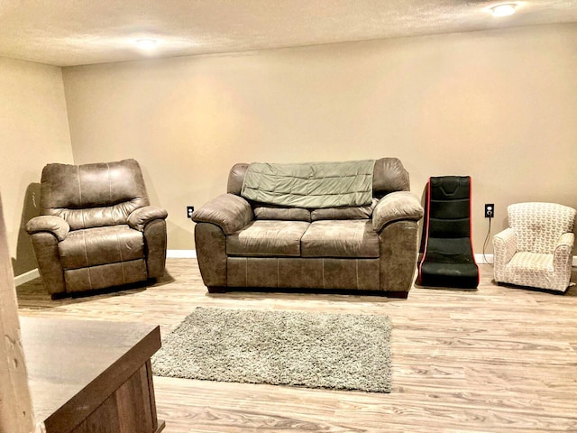living room featuring baseboards, a textured ceiling, and wood finished floors