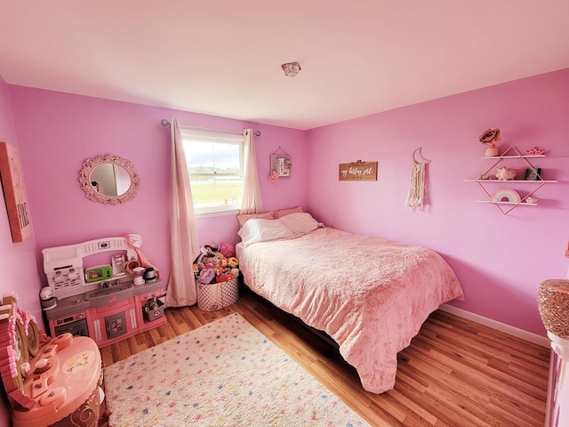 bedroom with baseboards and wood finished floors