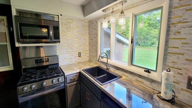 kitchen featuring light countertops, appliances with stainless steel finishes, decorative backsplash, and a sink